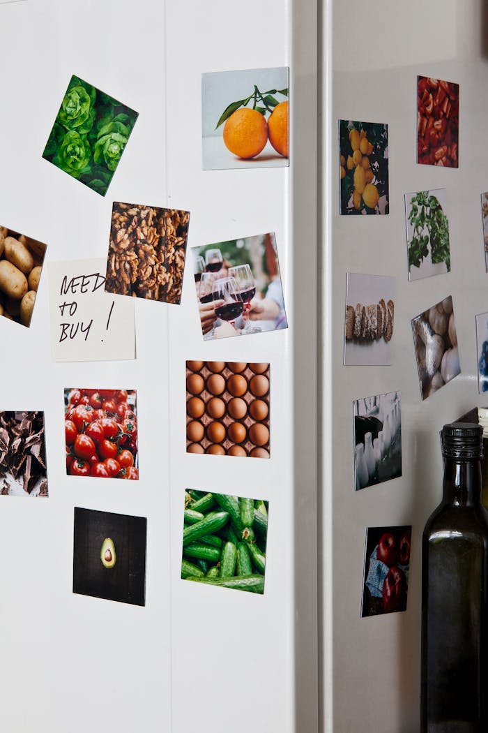 A close-up of various food-themed magnets on a kitchen fridge with a note saying 'Need to Buy!'